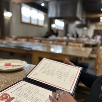 Fire & Sticks - a woman holding a menu in a restaurant - Steakhouses Near Me - High Point, North Carolina