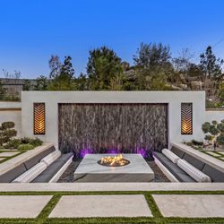 Calimingo Pools - Weeping water wall framed with our signature fire cages and a sunken fire pit with generous seating for 12 people
