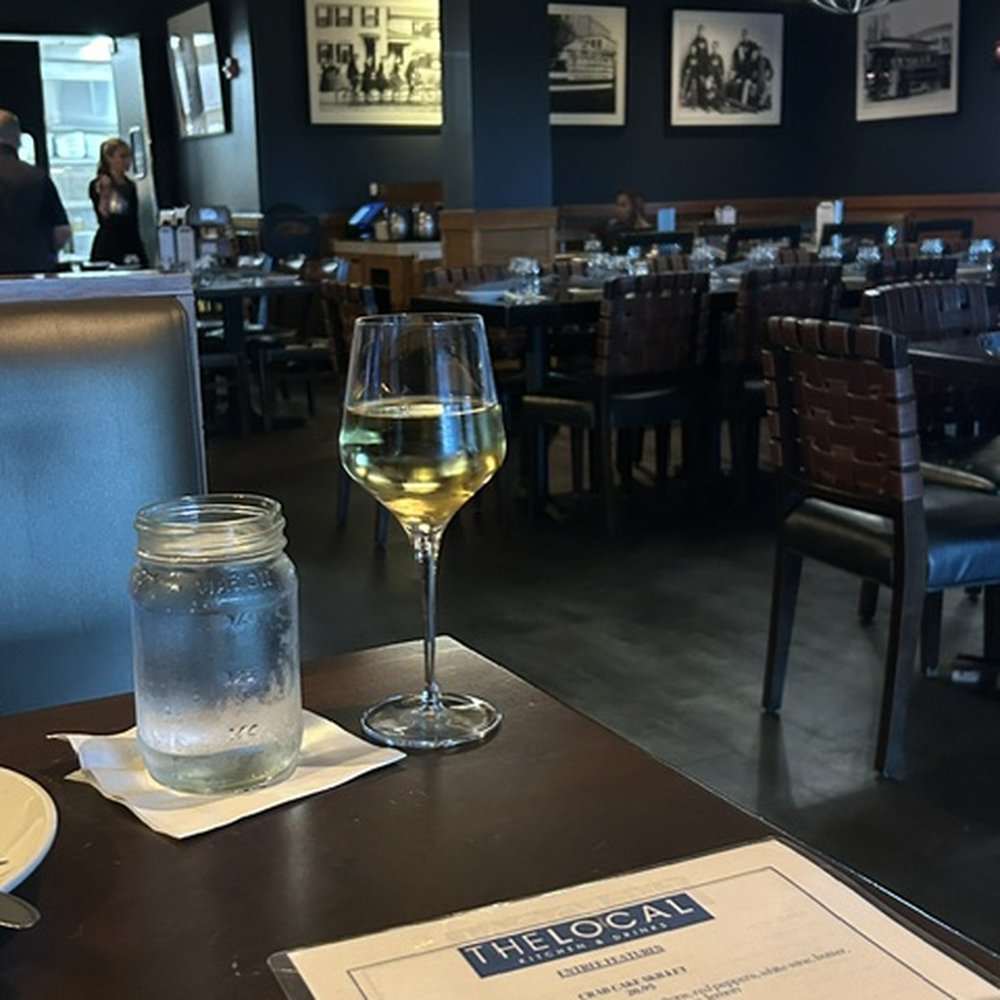 The Local Kitchen & Drinks - interior (background), chardonnay and water (foreground) - New American Near Me - Waltham, Massachusetts The Local Kitchen & Drinks - interior (background), chardonnay and water (foreground) - New American Near Me - Waltham, Massachusetts