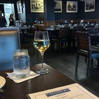 The Local Kitchen & Drinks - interior (background), chardonnay and water (foreground) - New American Near Me - Waltham, Massachusetts