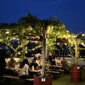 Rooftop Reds - a group of people sitting at tables under a pergol - Wineries Near Me - Brooklyn, New York