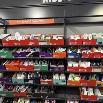 Nike - Children's shoes are arranged on shelves in a retail store, with a sign indicating a 30% discount on the entire wall. - Sports Wear Near Me - Central Valley, New York
