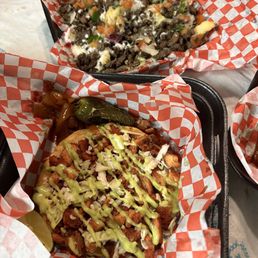 Pollo Vampiros & Asada Fries - Two baskets contain Mexican-style dishes: one with carne asada fries topped with green sauce, and another with a meat and cheese mixture with vegetables and melted cheese.