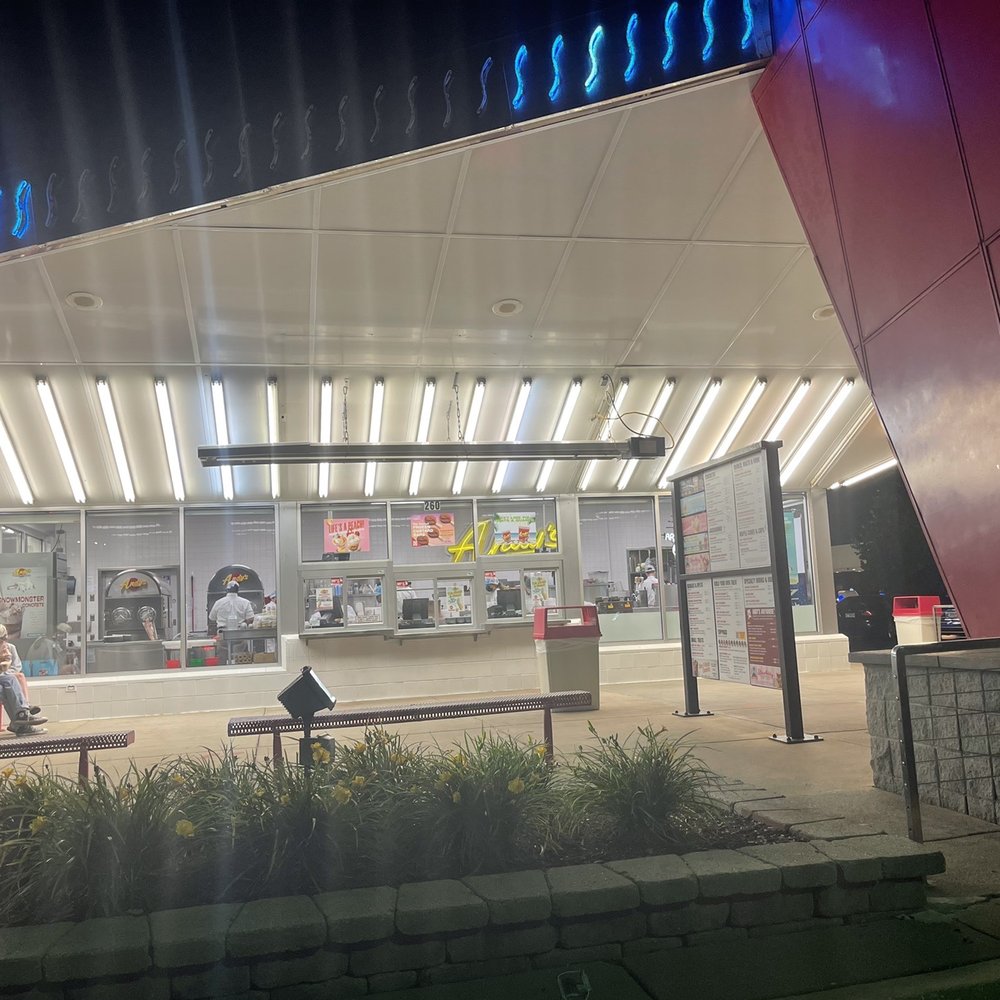 a woman sitting on a bench in front of a restaurant a woman sitting on a bench in front of a restaurant