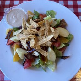bbq chix salad with oranges apples strawberries bacon feta cheese tortilla strips on top and barbecue ranch on the side