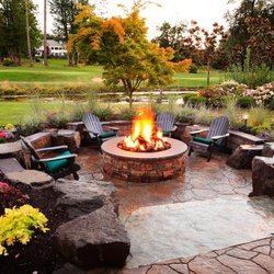 Houston Landscaping - Fire pit seating area, flagstone and large boulders, plants and trees.