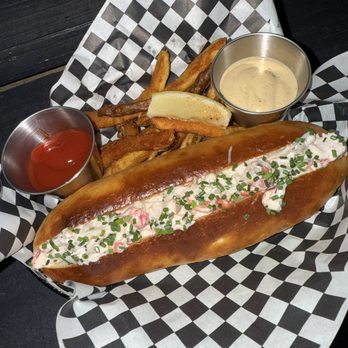 Anything - Lobster Roll - A lobster roll with chopped chives in a toasted bun, accompanied by French fries, ketchup, and a creamy dipping sauce on checkered paper. - Pizza Near Me - Brooklyn, New York