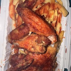 Chicken  wings with fries. Has bbq sauce and hot sauce all over it