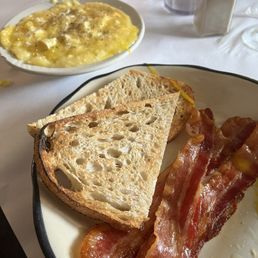 Two eggs over easy sourdough toast grits and bacon