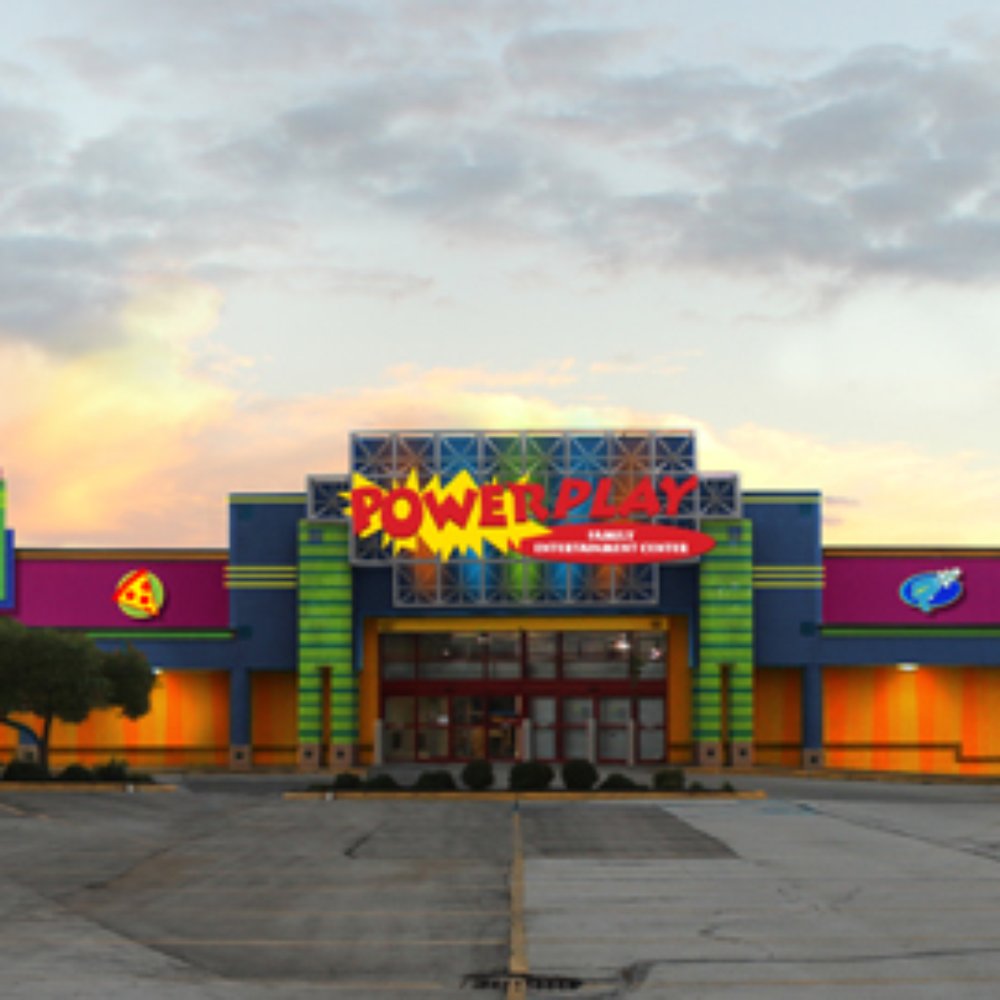 an empty parking lot in front of a brightly lit building an empty parking lot in front of a brightly lit building