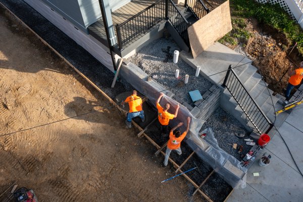 Multi-Unit Front Hardscape & Entry Upgrade - This large-scale project involved a full front yard transformation for a multi-family property. Our team excavated and graded the lot, installed modern concrete staircases with integrated landings, and constructed retaining walls to manage elevation changes. The finished space includes durable walkways, clean entry access, and elegant evening lighting for both safety and curb appeal. From morning setup to final night shots, this project showcases the precision and pace of our crew. Multi-Unit Front Hardscape & Entry Upgrade - This large-scale project involved a full front yard transformation for a multi-family property. Our team excavated and graded the lot, installed modern concrete staircases with integrated landings, and constructed retaining walls to manage elevation changes. The finished space includes durable walkways, clean entry access, and elegant evening lighting for both safety and curb appeal. From morning setup to final night shots, this project showcases the precision and pace of our crew.