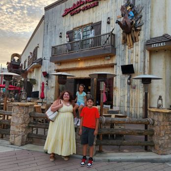 Saddle Ranch - a couple of people standing in front of a building - Steakhouses Near Me - Orange, California
