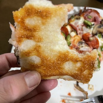 Jet's Pizza - a hand holding a piece of pizza - Pizza Near Me - Tomball, Texas