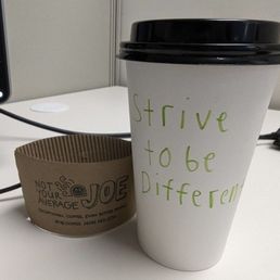 Cup of coffee with Strive to be different hand written
