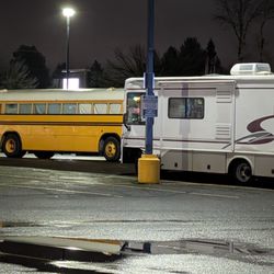 Bi-Mart - RV & school bus conversion parked at Bi-Mart parking lot next to no overnight parking sign