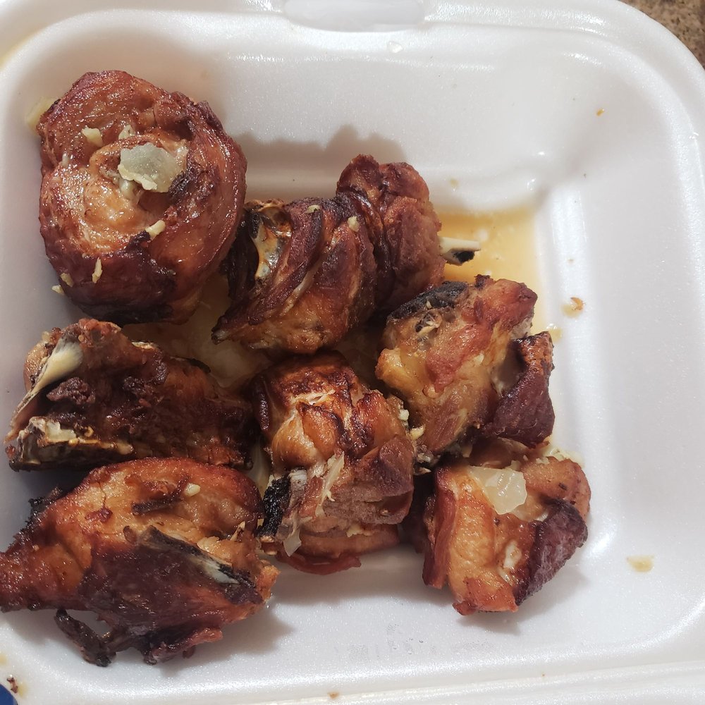 a white styrofoam container filled with chicken wings a white styrofoam container filled with chicken wings