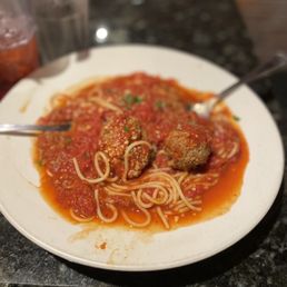 My Spaghetti And Meatballs With Red Sauce! - Spaghetti with meatballs in tomato sauce served on a white plate, with two forks placed on the dish, set on a dark countertop.