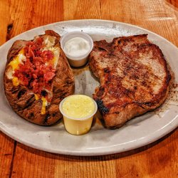 Click's Steakhouse - The pork chop, perfectly seared, a culinary delight. The potato? A crispy cocoon with a fluffy heart. Heaven on a plate!