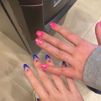 Venezia Nail Spa - Two hands with manicured nails, one pink with designs and the other blue with dots, are positioned near a vending machine. - Nail Salons Near Me - Glenview, Illinois