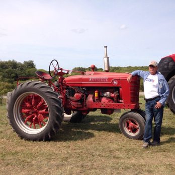 Big Pine Lodge - a man standing next to a red tractor - Pizza Near Me - Perham, Minnesota