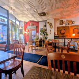 Cafe area - A cafe interior featuring wooden tables and chairs, with a decorated wall including musical instruments and framed pictures, near large windows.
