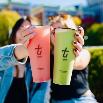 TBaar - Eagan - two women sitting on a bench, one holding a drink and the other holding a drink - Bubble Tea Near Me - Eagan, Minnesota TBaar - Eagan - two women sitting on a bench, one holding a drink and the other holding a drink - Bubble Tea Near Me - Eagan, Minnesota
