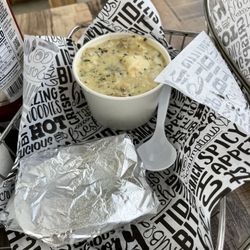 Ship Out - Cup of seafood chowder with a piece of toasted bread.