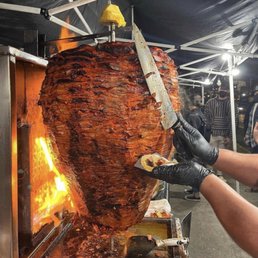 a man holding a knife over a large meat a man holding a knife over a large meat