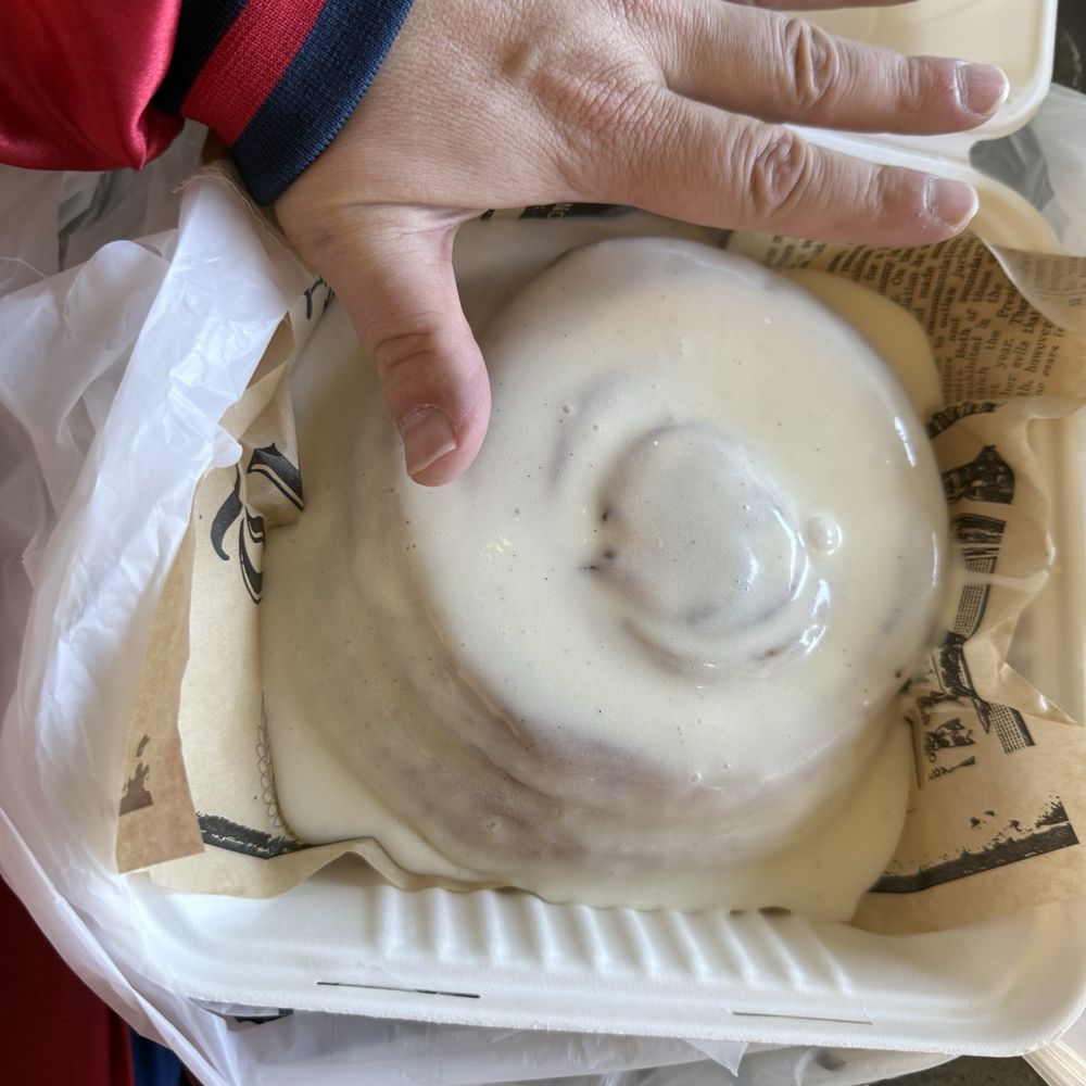 Richter Bakhaus - Cinnamon roll with hand for scale - Coffee & Tea Near Me - Boerne, Texas Richter Bakhaus - Cinnamon roll with hand for scale - Coffee & Tea Near Me - Boerne, Texas