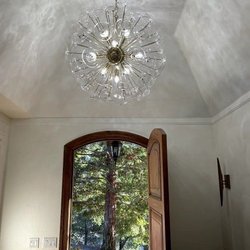 FS Electric - A sunlit entryway features a grand, spherical glass chandelier that creates intricate patterns on the vaulted ceiling...