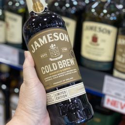 a person holding a bottle of jameson cold brew