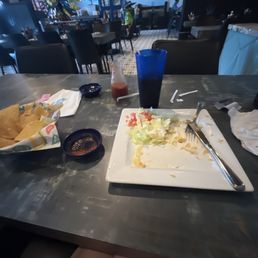 Fully eaten chicken quesadilla with rice. Half eaten chips and salsa with a sweet tea to drink.