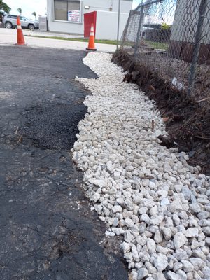 Gravel drainage installed - A strip mall parking lot in Jensen Beach always floods during rainstorms. So, I removed all sod, dug out a trench following the fence line and applied 3/4'' white stone for drainage. Parking lot has not flooded since.
