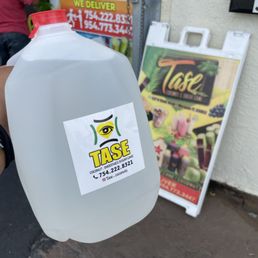 a hand holding a gallon of tasty