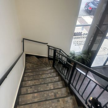 UroPartners - The stairs. - An indoor staircase with tiled steps and black metal railings, adjacent to a large window revealing parked cars outside. - Urologists Near Me - Chicago, Illinois