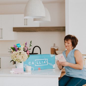 Callia Flowers - Callia bouquet in vase next to delivery box, add-ons and customer - Florists Near Me
