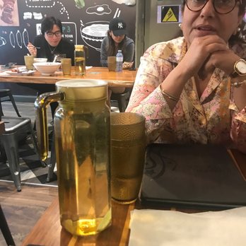 Magic Noodle - a woman sitting at a table with a glass of beer - Noodles Near Me - North York, Ontario