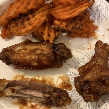 Big City Wings - Kids Bone In Wings impressed with the size and very saucy sweet potato fries soggy but it was DoorDash so to be expected - A plate with fried chicken wings, waffle fries, and sauce, served on a decorative paper plate, likely from a casual dining or takeout setting. - Chicken Wings Near Me - Spring, Texas