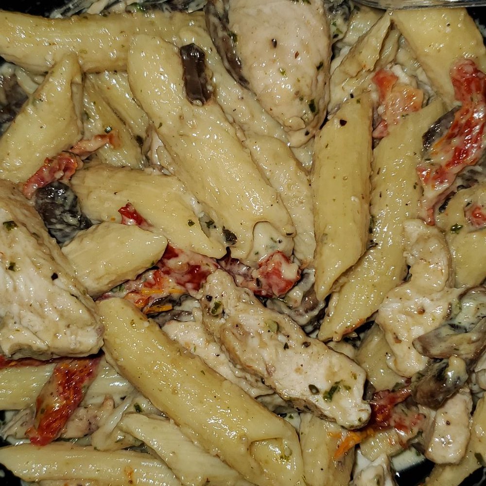 a plate of pasta with chicken and tomatoes