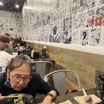 Senzu Noodle Bar And Boba - My mom enjoying her Shio Pork Ramen amist the anime themed wall - Ramen Near Me - West Melbourne, Florida Senzu Noodle Bar And Boba - My mom enjoying her Shio Pork Ramen amist the anime themed wall - Ramen Near Me - West Melbourne, Florida