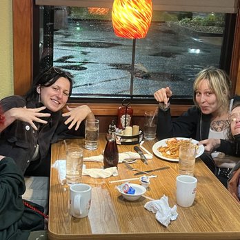 Denny's - Four women are seated at a restaurant table with food, drinks, and condiments, smiling and posing for the photo. - Diners Near Me - Effingham, Illinois