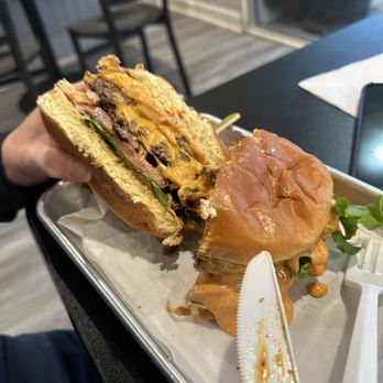 The Burger Life - Do you see all that cheese?  It looks amazing but it tasted like a salt shaker. - A cheeseburger with melted cheese, lettuce, and other toppings is partially eaten and placed on a metal tray at a restaurant. - Burgers Near Me - Naperville, Illinois