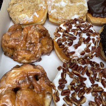 Spudnut Donuts - Good eats - A box of assorted donuts featuring toppings like cinnamon sugar, chocolate glaze, and pecans, with some glazed and frosted varieties. - Donuts Near Me - Berea, Ohio