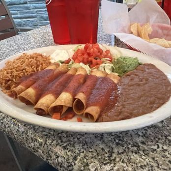 Chuy's - A Mexican meal featuring enchiladas with sauce, rice, refried beans, and toppings like lettuce, tomato, and guacamole on a granite table. - Mexican Near Me - Florence, Kentucky