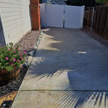Ruiz Landscape - Round river rock fringes installed on either side of (pre-existing) cement pad. - Landscaping Near Me - Hemet, California