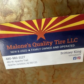 Malone's Quality Tire - A business card for Malone's Quality Tire LLC displays the company name, contact phone number, address, and manager's name. The card includes social media icons for Facebook and Instagram. The background has a design with a star and rays in red, yellow, and blue colors, and the card is placed on a textured surface. - Tires Near Me - Apache Junction, Arizona