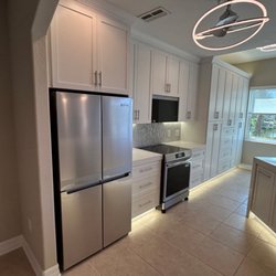Modern kitchen featuring white custom cabinetry, sleek countertops, and warm under-cabinet lighting.