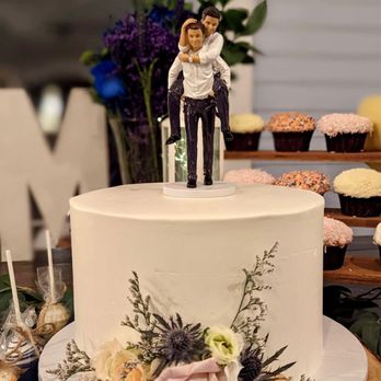 Top Tier Treats - Circular wedding cake lined with flowers at the bottom and topped with a wedding topper of two guys piggybacking - Bakeries Near Me - Los Angeles, California Top Tier Treats - Circular wedding cake lined with flowers at the bottom and topped with a wedding topper of two guys piggybacking - Bakeries Near Me - Los Angeles, California