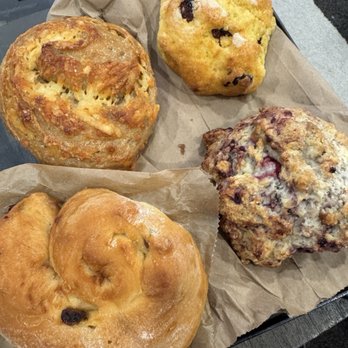 The Cheeseboard Collective - Five baked items, including bread and muffins, are arranged on parchment paper, showcasing different textures and ingredients. - Bakeries Near Me - Berkeley, California