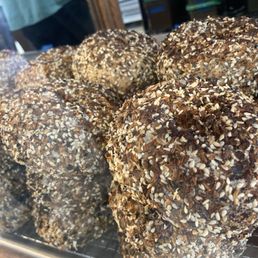 Everything Bagels! - Several bagels covered with sesame seeds and other toppings are displayed on a wire rack at a market stall.